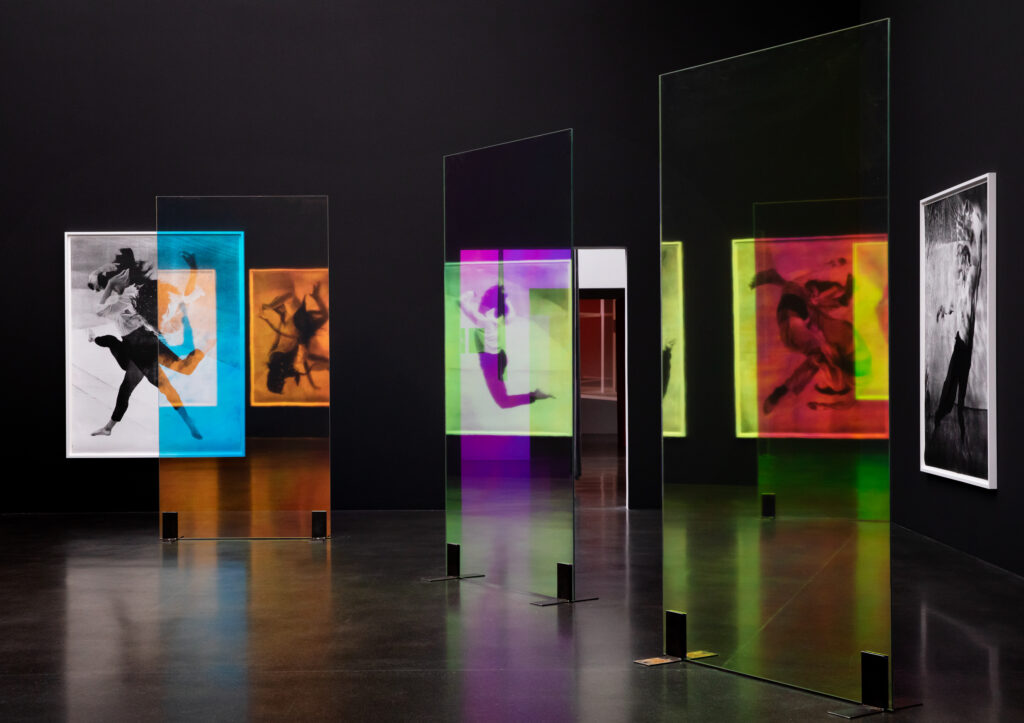 Sophie und Karl Binding Stiftung | Binding Sélection d’Artistes Ausstellungsansicht Shriana Shahbazi. Dunkler Raum mit farbigen Bildern von Menschen in Bewegung.